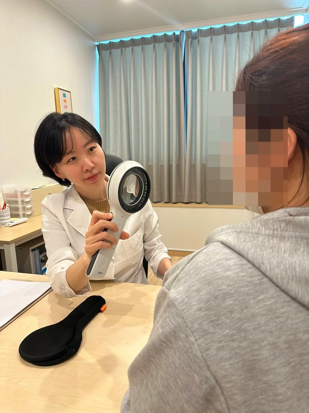 피부 확대경으로 얼굴 진단하는 모습