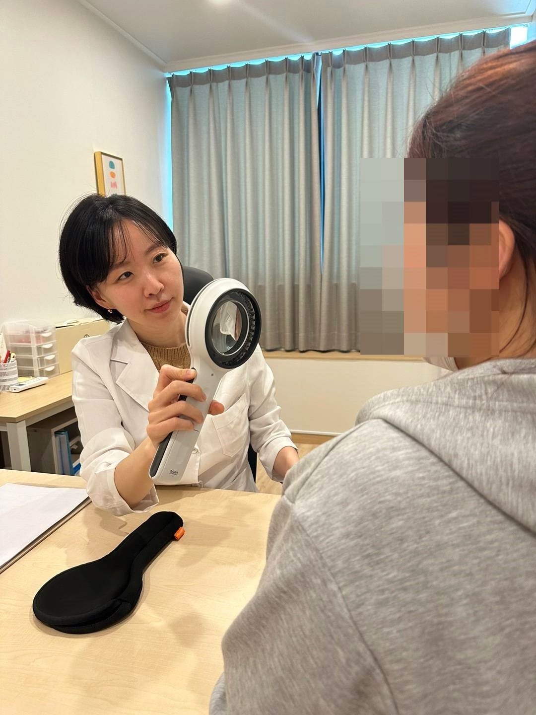 확대경으로 환자 피부를 살펴보는 비립종 진찰 장면